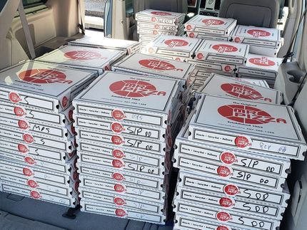 Car loaded with stacks of boxed pizzas in white and red containers.