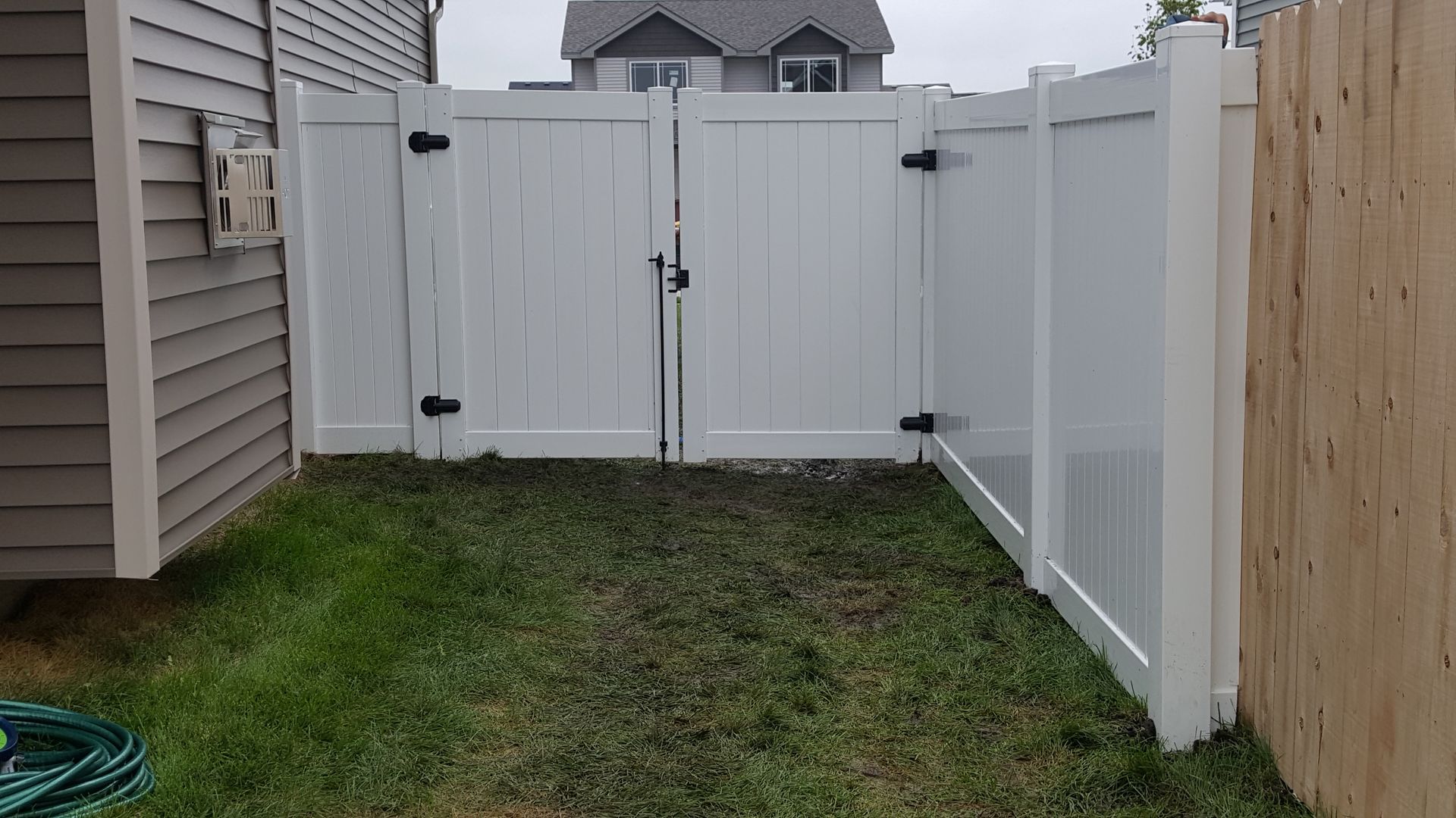 A white fence is in the backyard of a house.