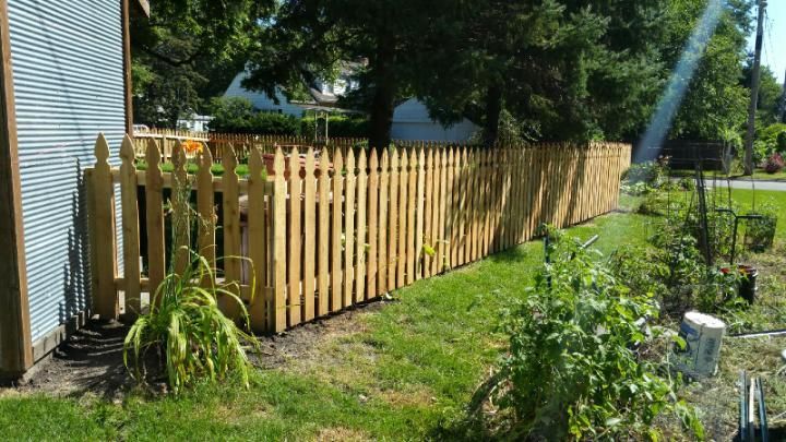 A wooden picket fence surrounds a lush green yard.