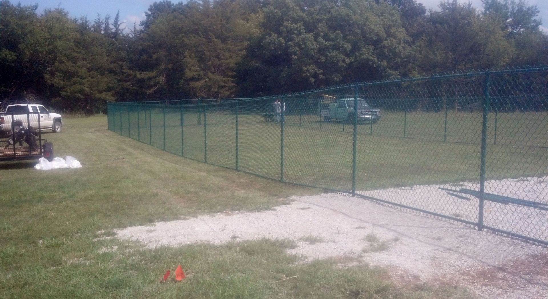 A chain link fence is surrounding a large grassy field.