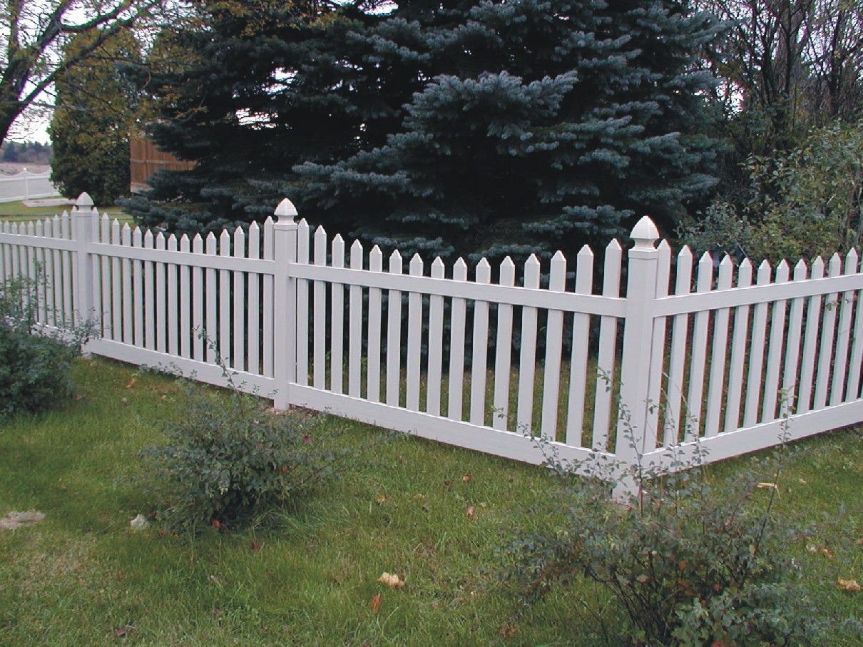 A white picket fence with trees in the background
