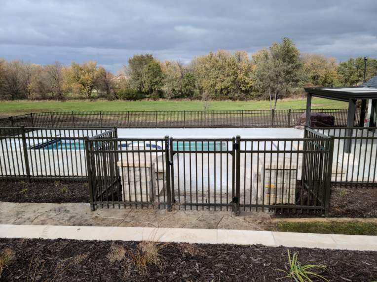 A large swimming pool surrounded by a fence on a cloudy day.
