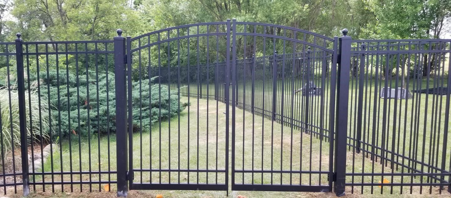 A black wrought iron fence surrounds a lush green yard.