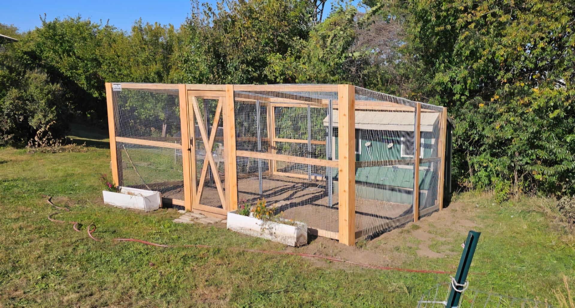 A wooden chicken coop is sitting in the middle of a grassy field.