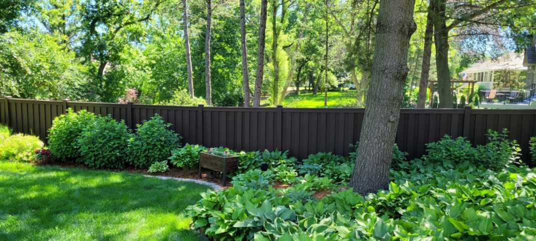 A backyard with a wooden fence and trees in the background.