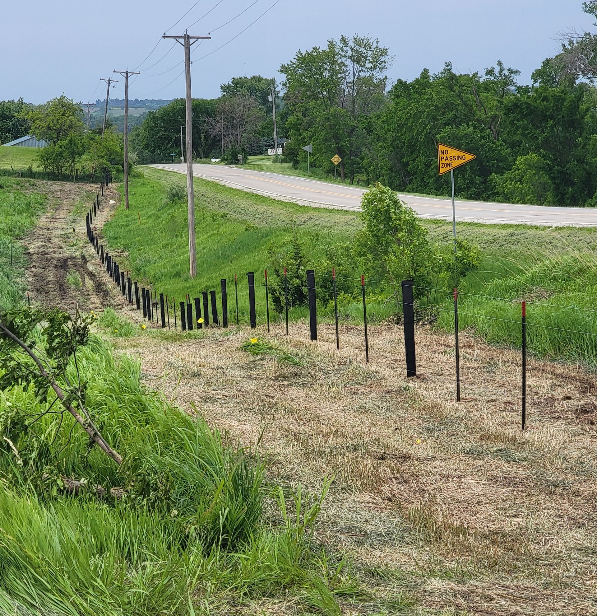 A fence surrounds a grassy field next to a road.