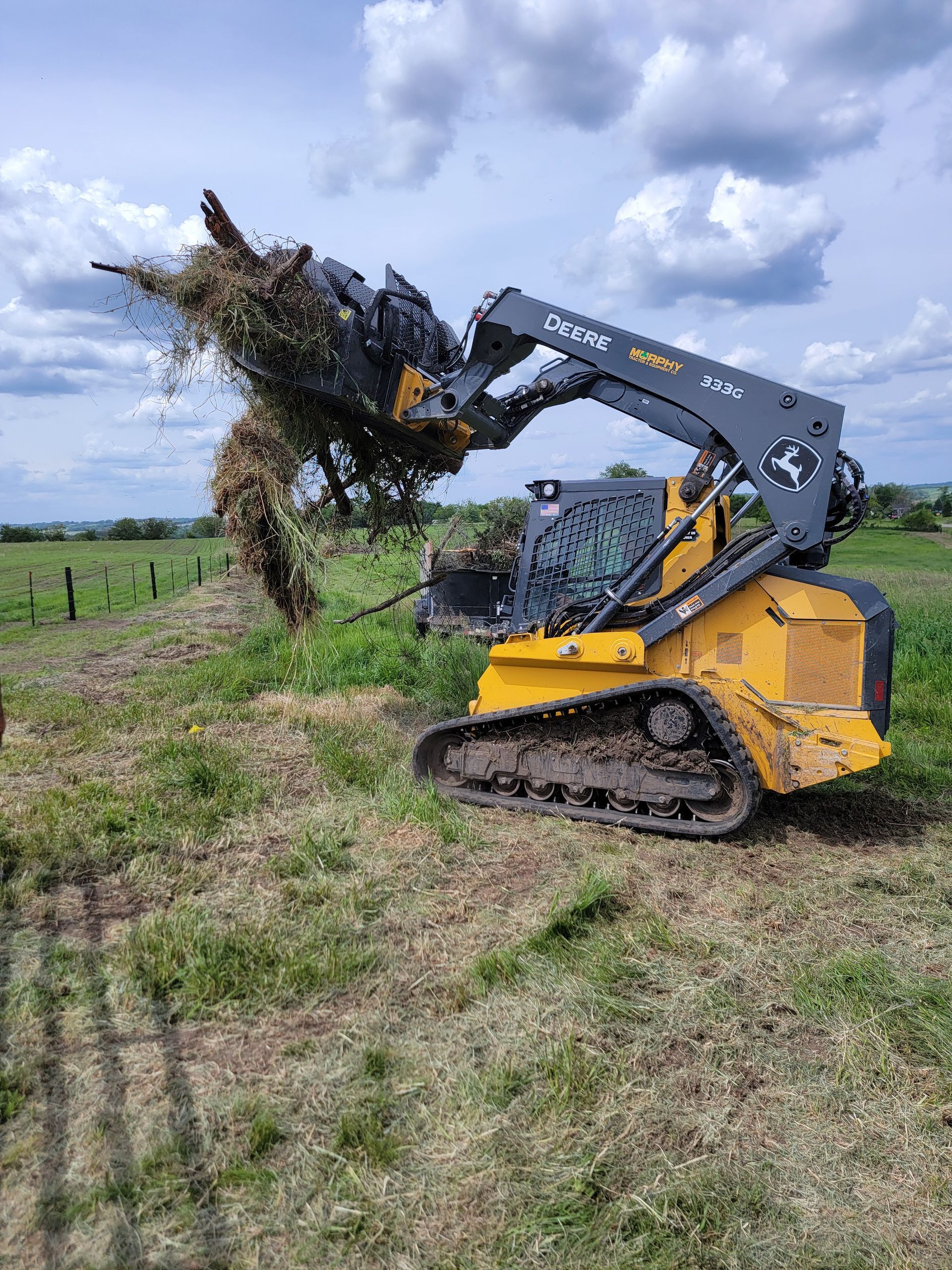 A bulldozer is cutting a tree in a field.