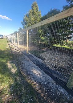 A wooden fence with a wire fence surrounding a field.