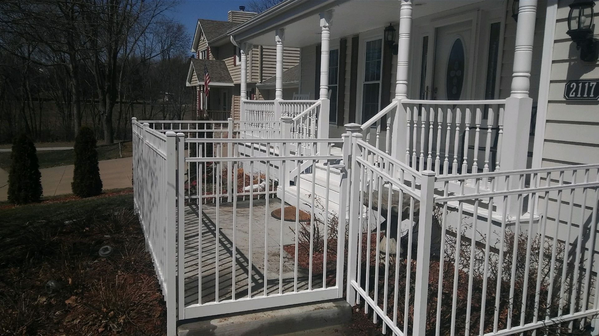 A white fence surrounds a porch of a house
