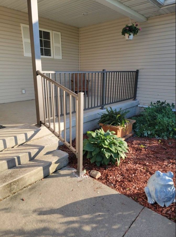 A porch with a metal railing and stairs leading up to it.