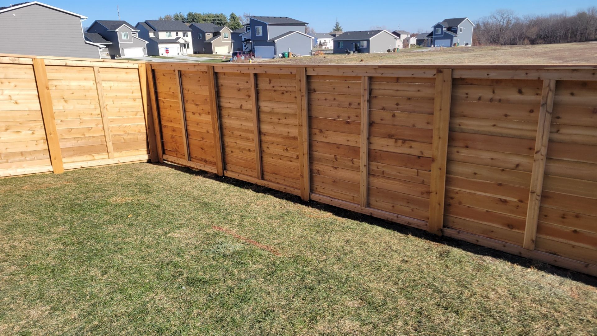 A wooden fence is in the backyard of a house.