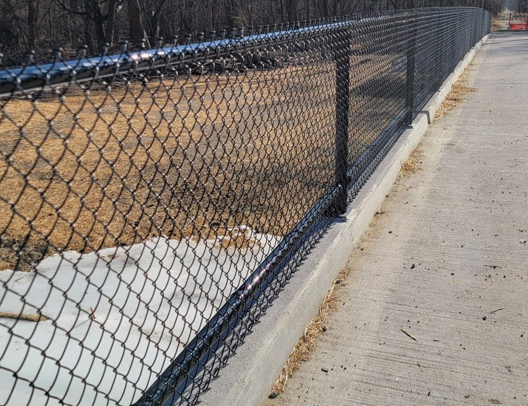 A chain link fence is along the side of a road.