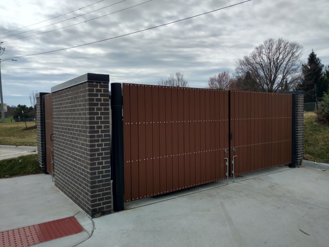 A wooden gate is sitting next to a brick wall.