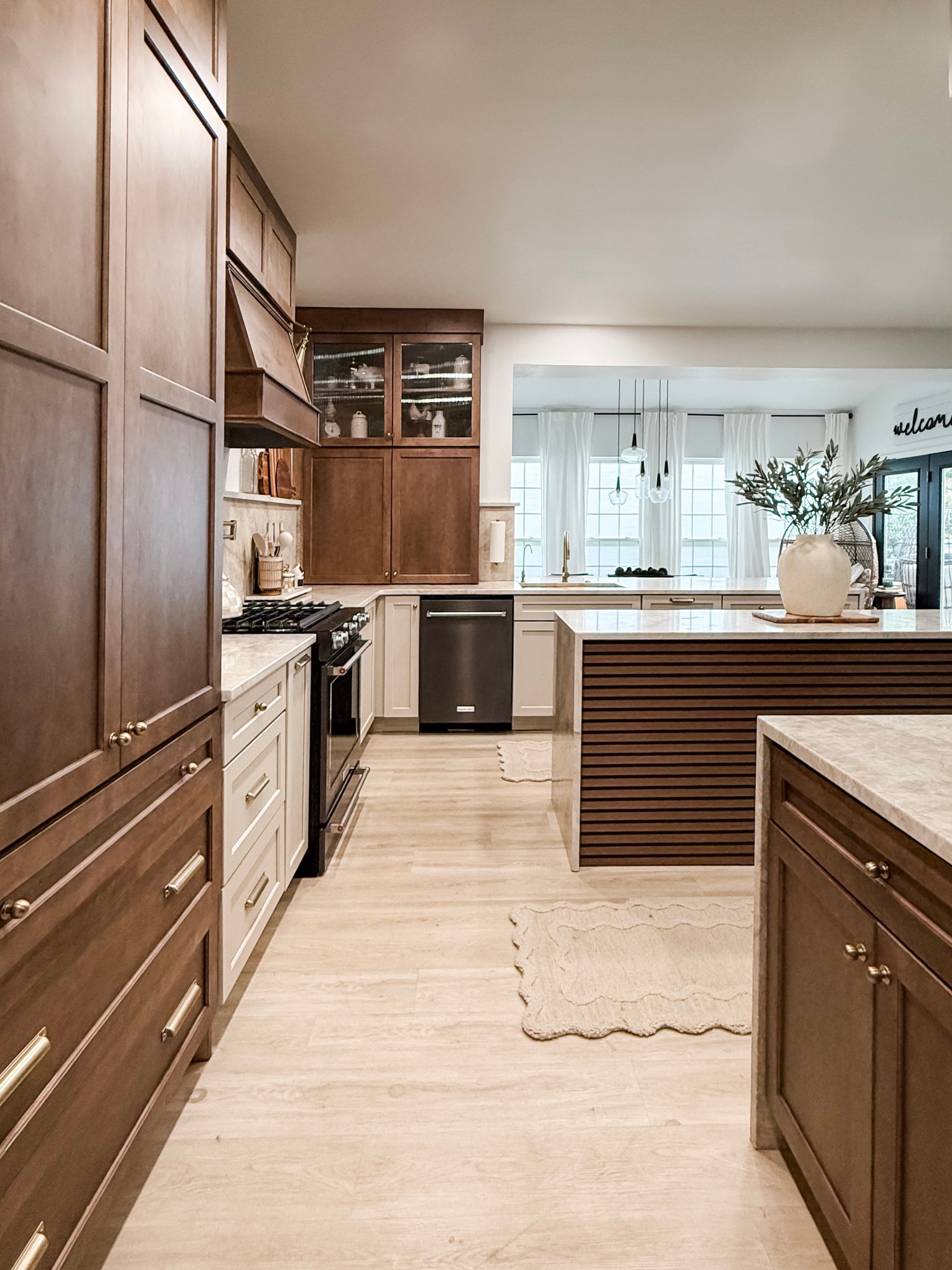 Modern kitchen with wood cabinets, light tile floor, and a view into a bright dining area