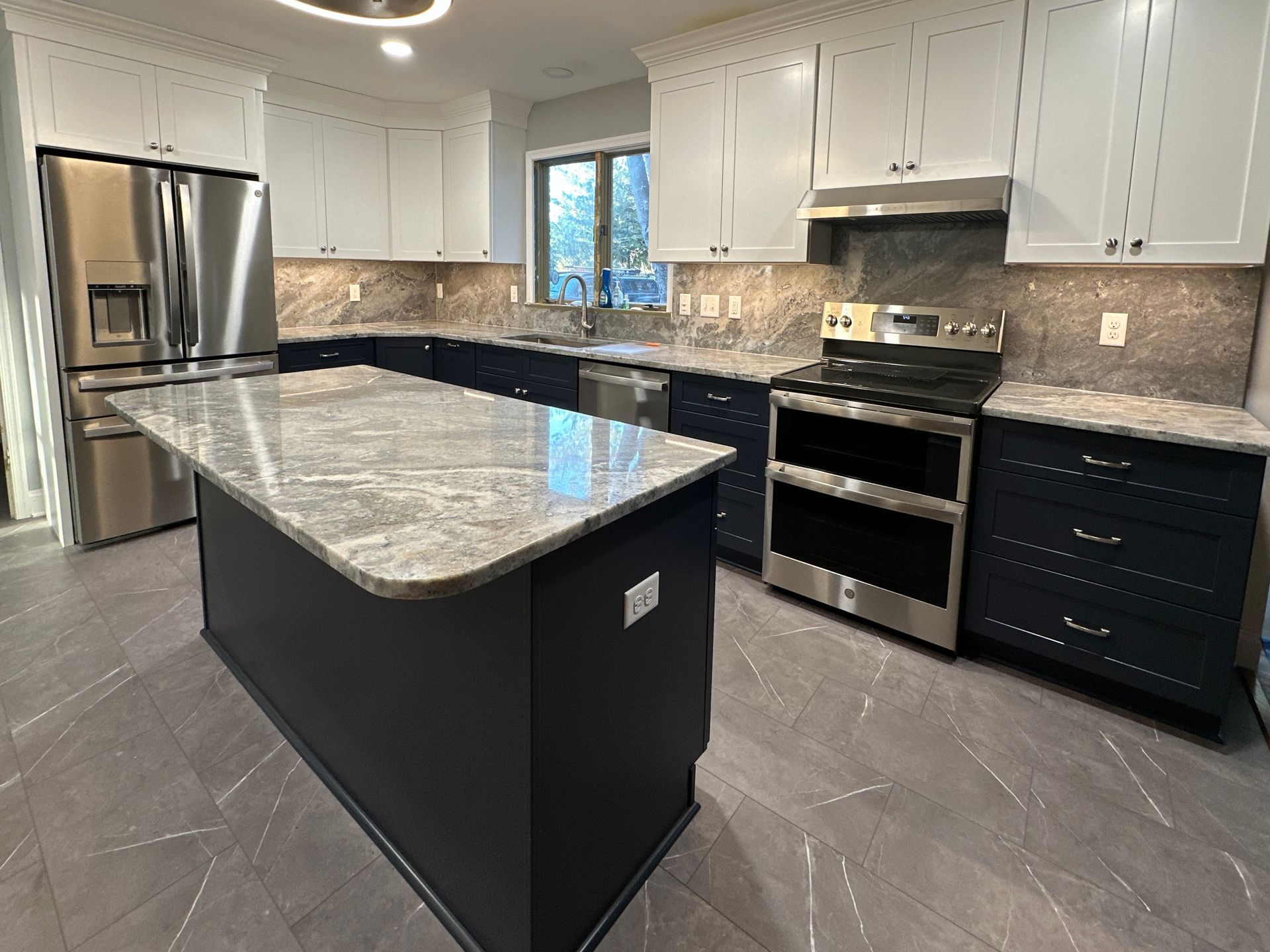 Modern kitchen with white cabinets, black island, stainless steel appliances, and gray tile floor