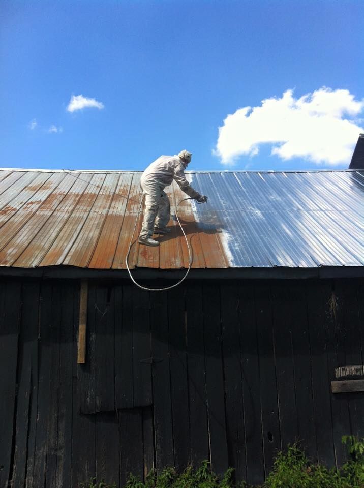 A man is spray painting the roof of a building
