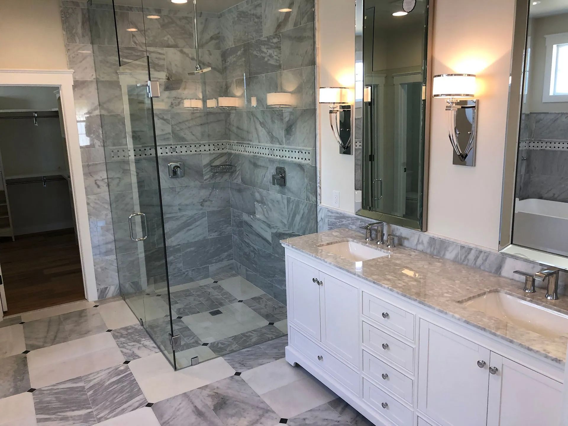 A bathroom with a walk in shower, sink and mirror.