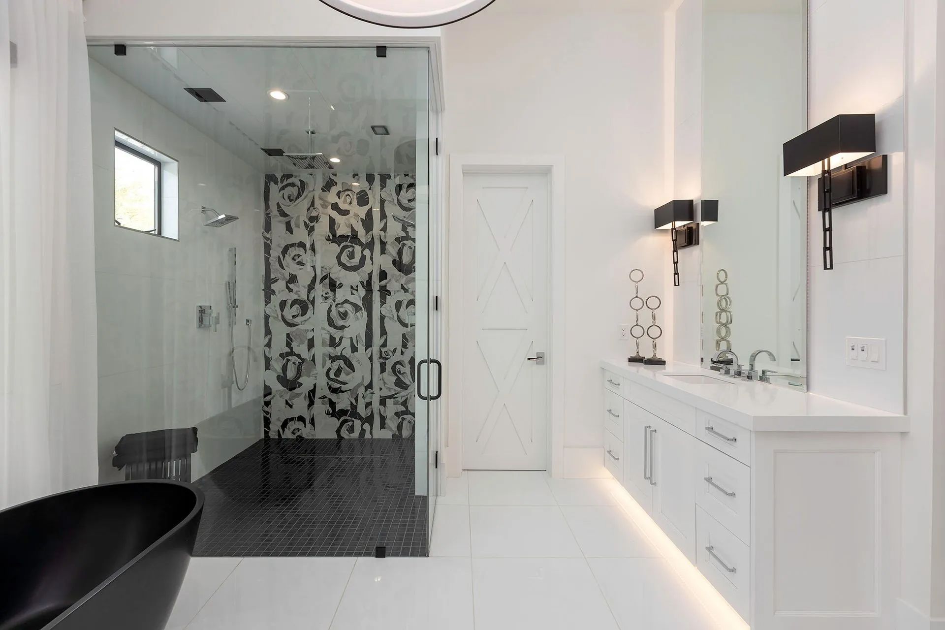 A bathroom with a black tub, sink, mirror and shower.
