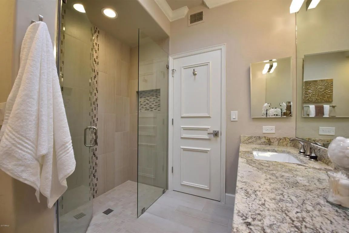 A bathroom with a walk in shower, sink and mirror.