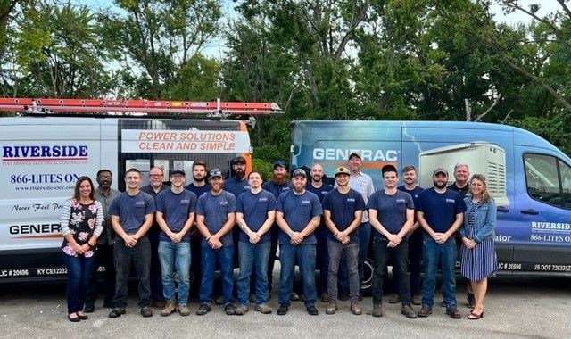 Group of utility workers in navy uniforms standing in front of parked service trucks outdoors.