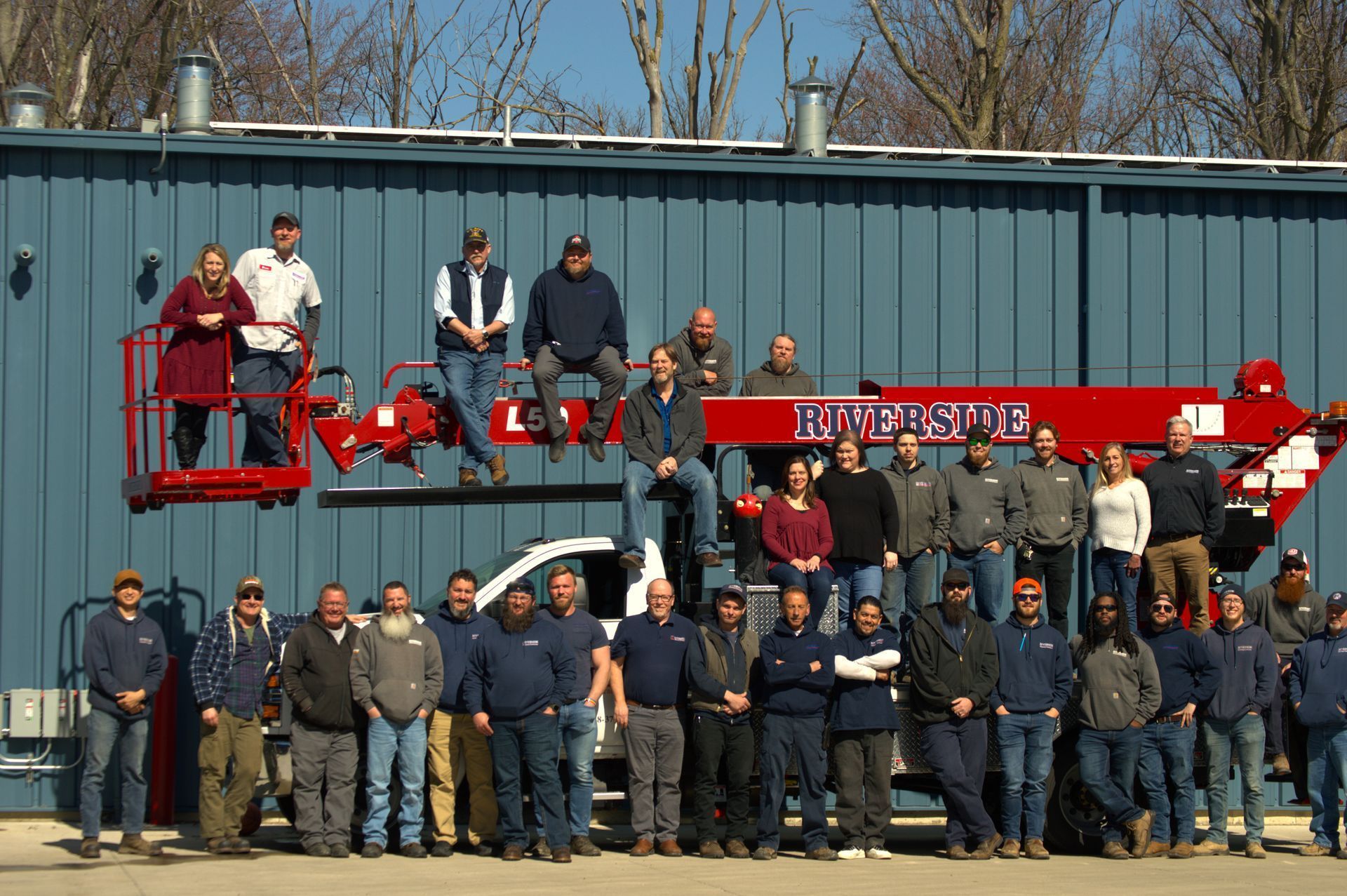 Group of people posing with a red fire truck in front of a blue building