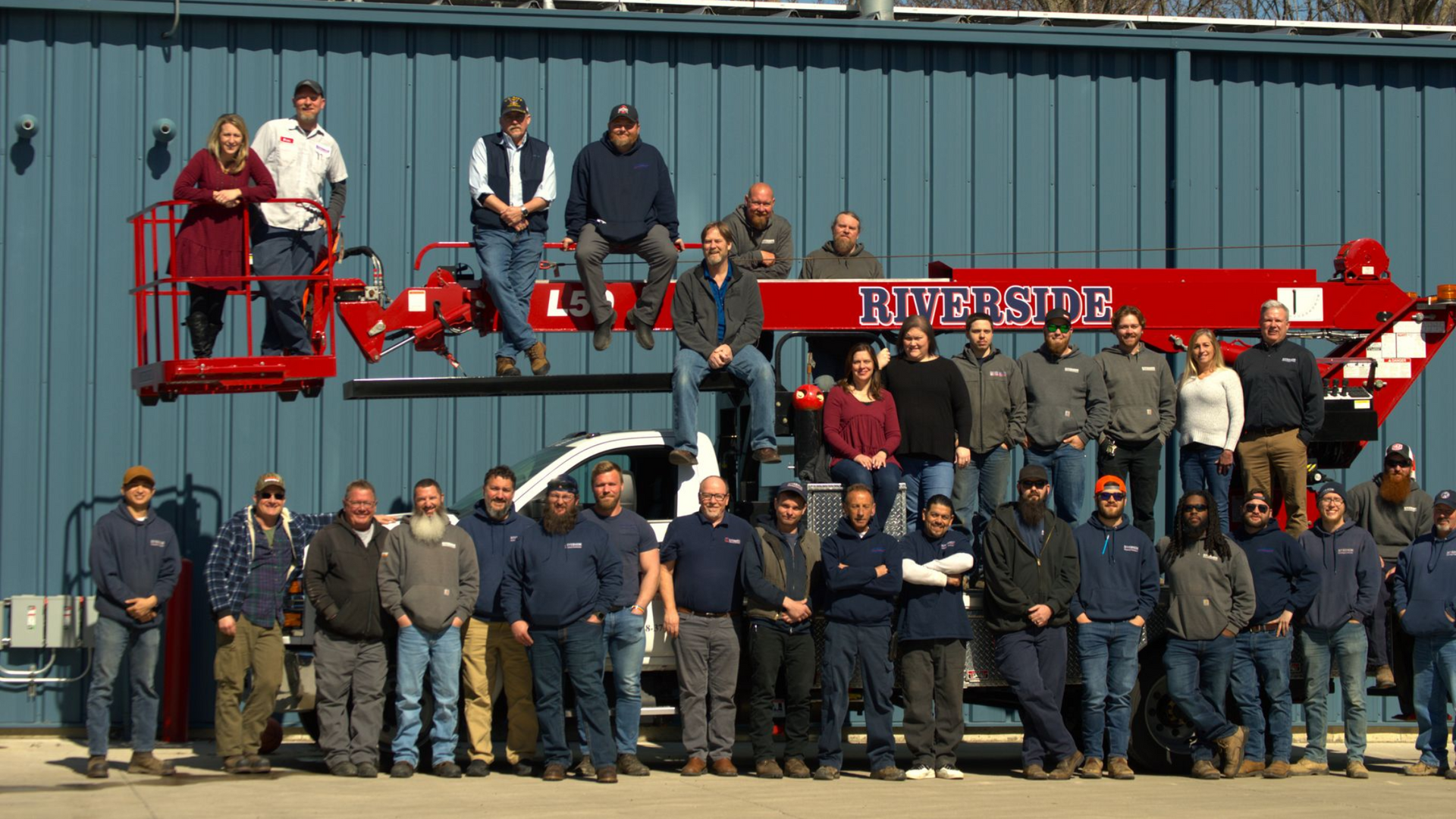 Group of people standing in front of a Riverside truck with generator advertisement.