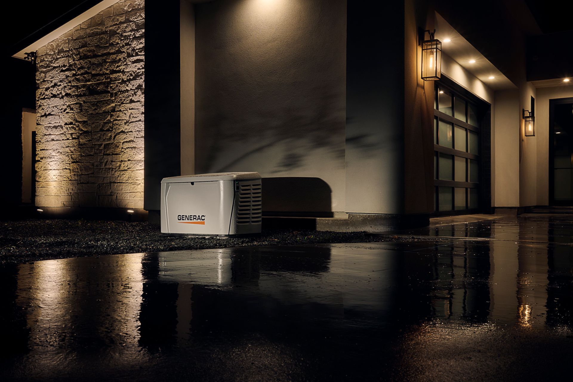 White portable generator on wet pavement outside a building at night, with reflections on the ground