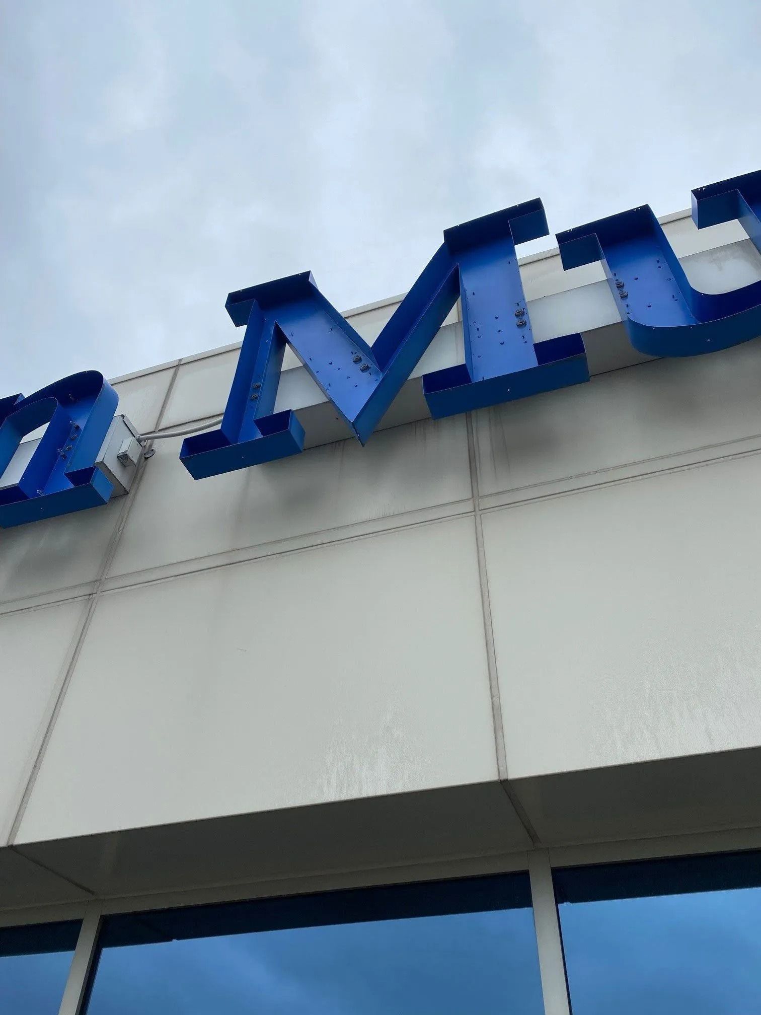 Blue letters on a building facade against a cloudy sky