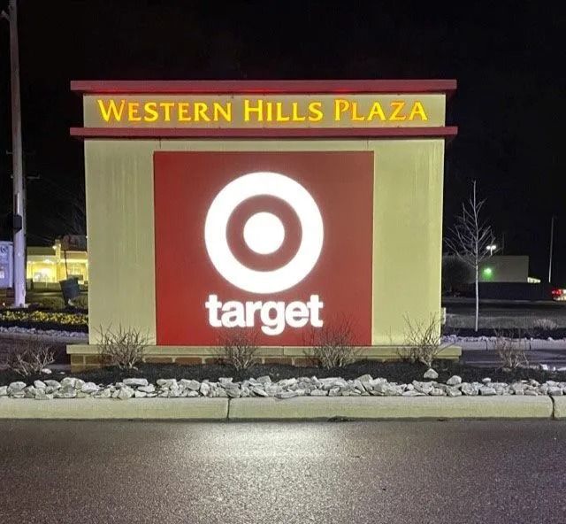 Target sign at Western Hills Plaza at night, lit in red and yellow beside a parking lot.