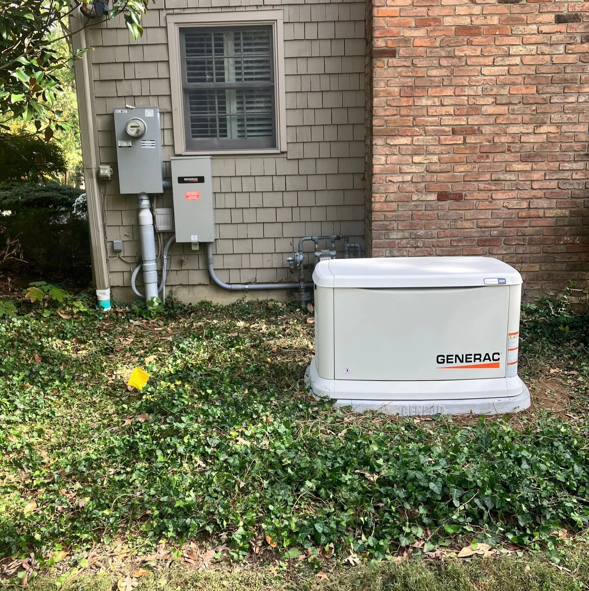 Outdoor HVAC unit beside brick wall and utility meters in a grassy yard