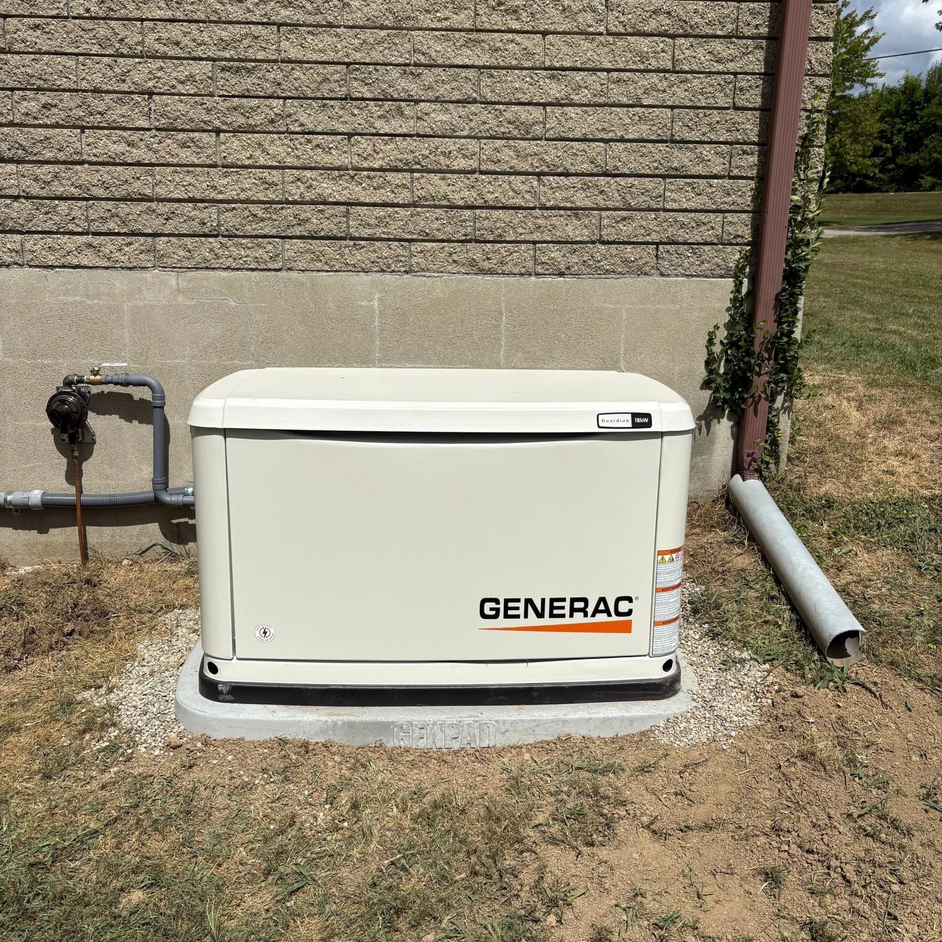 Generac home generator beside a house wall on a concrete pad