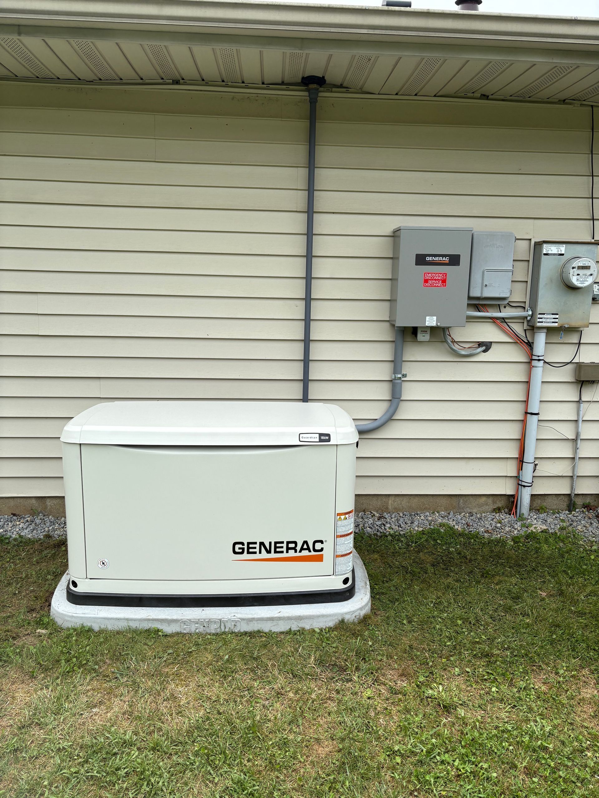 White Generac backup generator beside a house wall with electrical meter and conduit