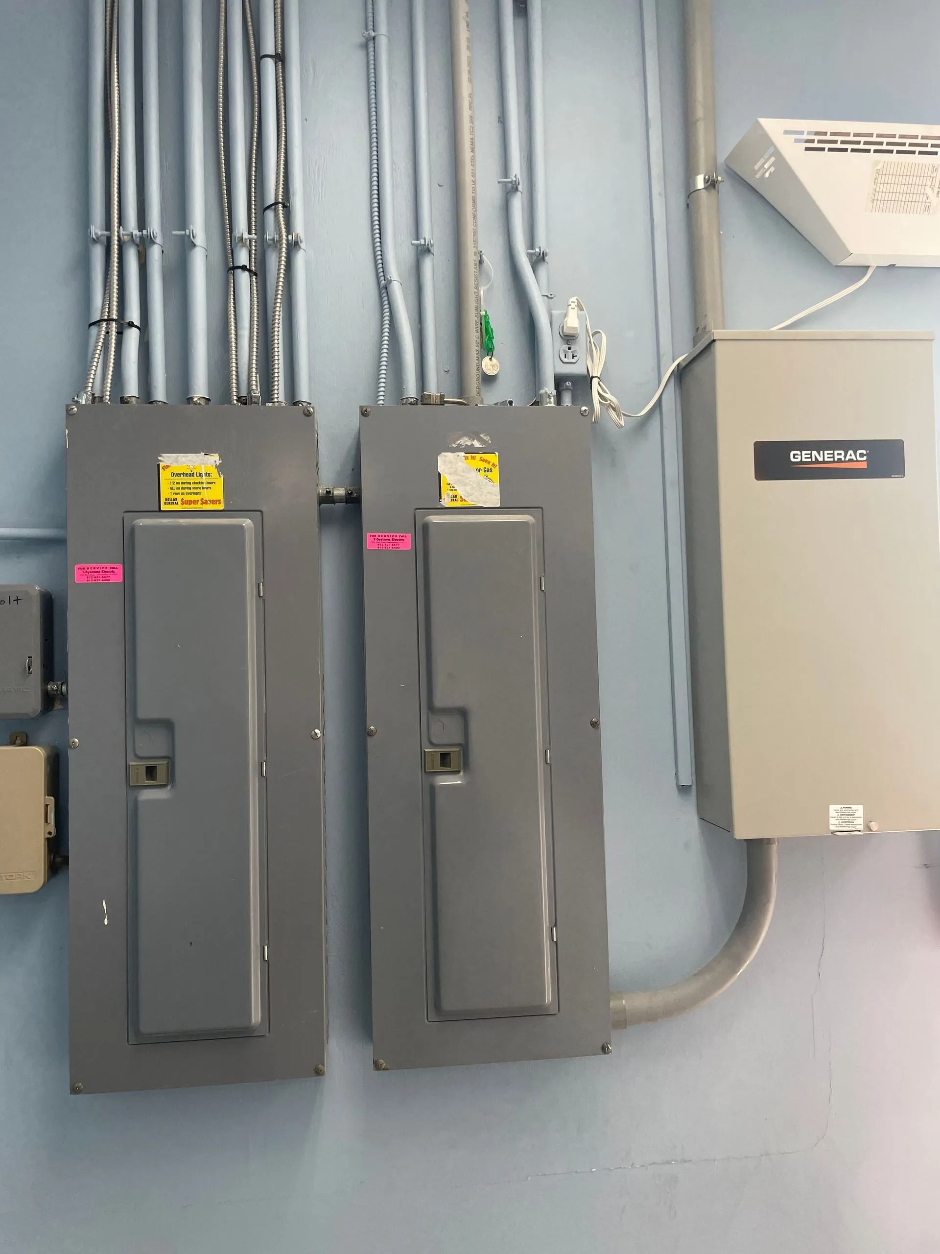 Electrical panels and conduit mounted on a gray wall in an industrial room