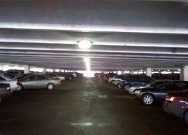 Dimly lit parking garage with rows of parked cars on both sides.