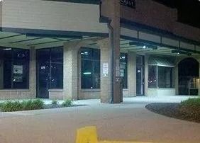 Empty storefront at night with lit walkway and columns in a shopping plaza