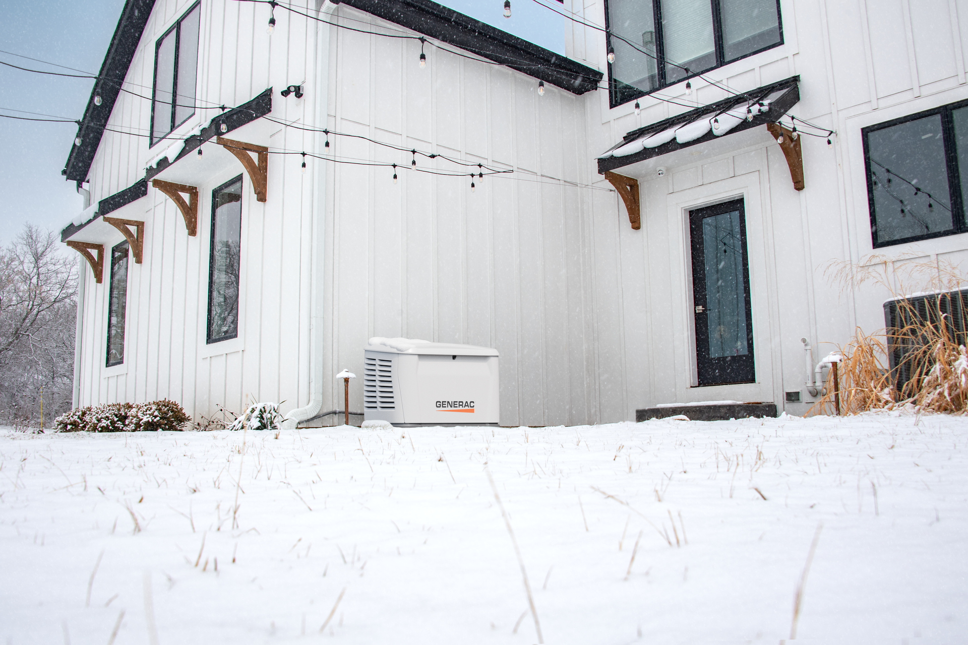Snow-covered white house exterior with black-trimmed windows and a small utility unit outside