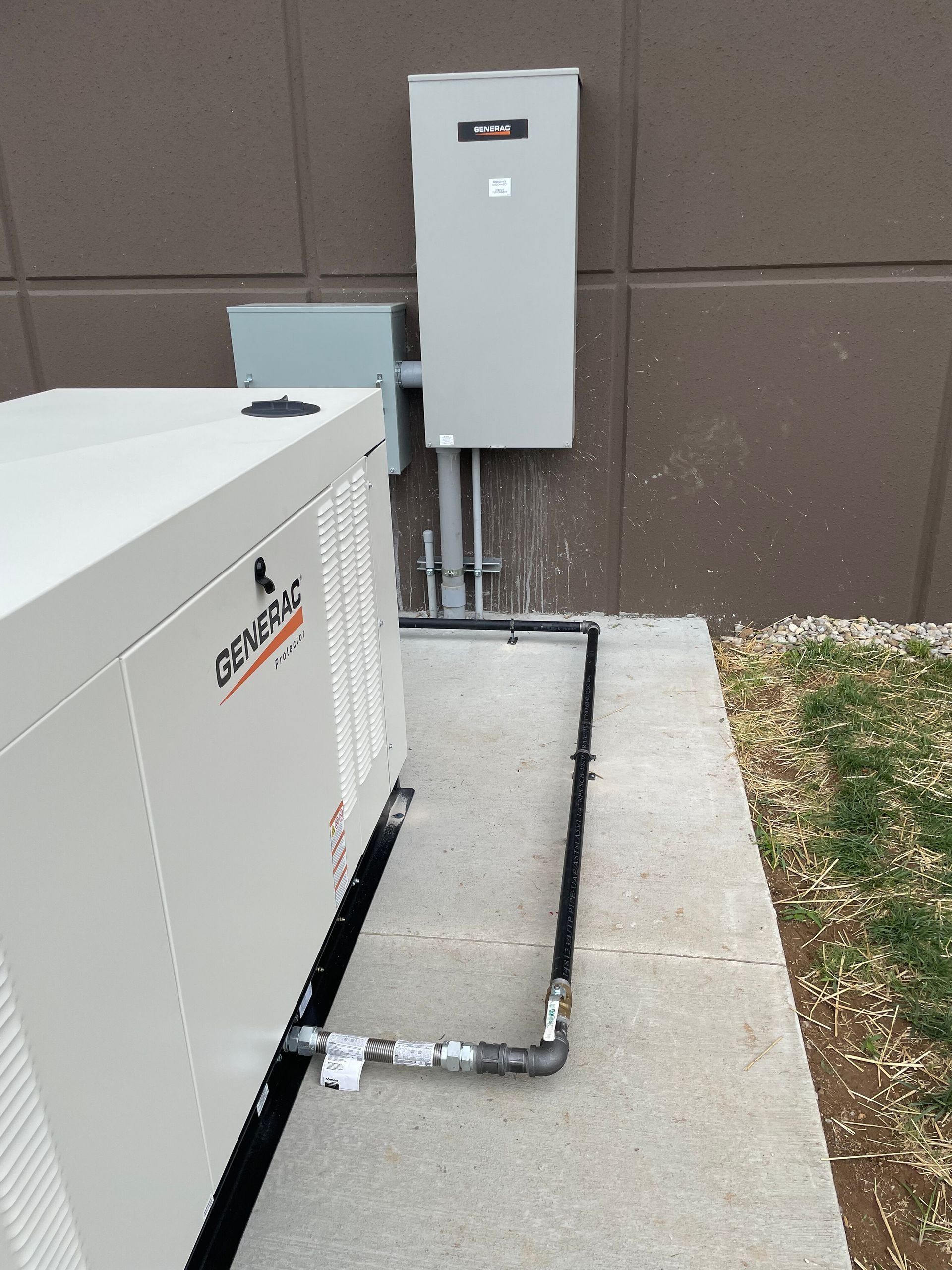 Outdoor electrical equipment with conduit beside a building wall and gravel