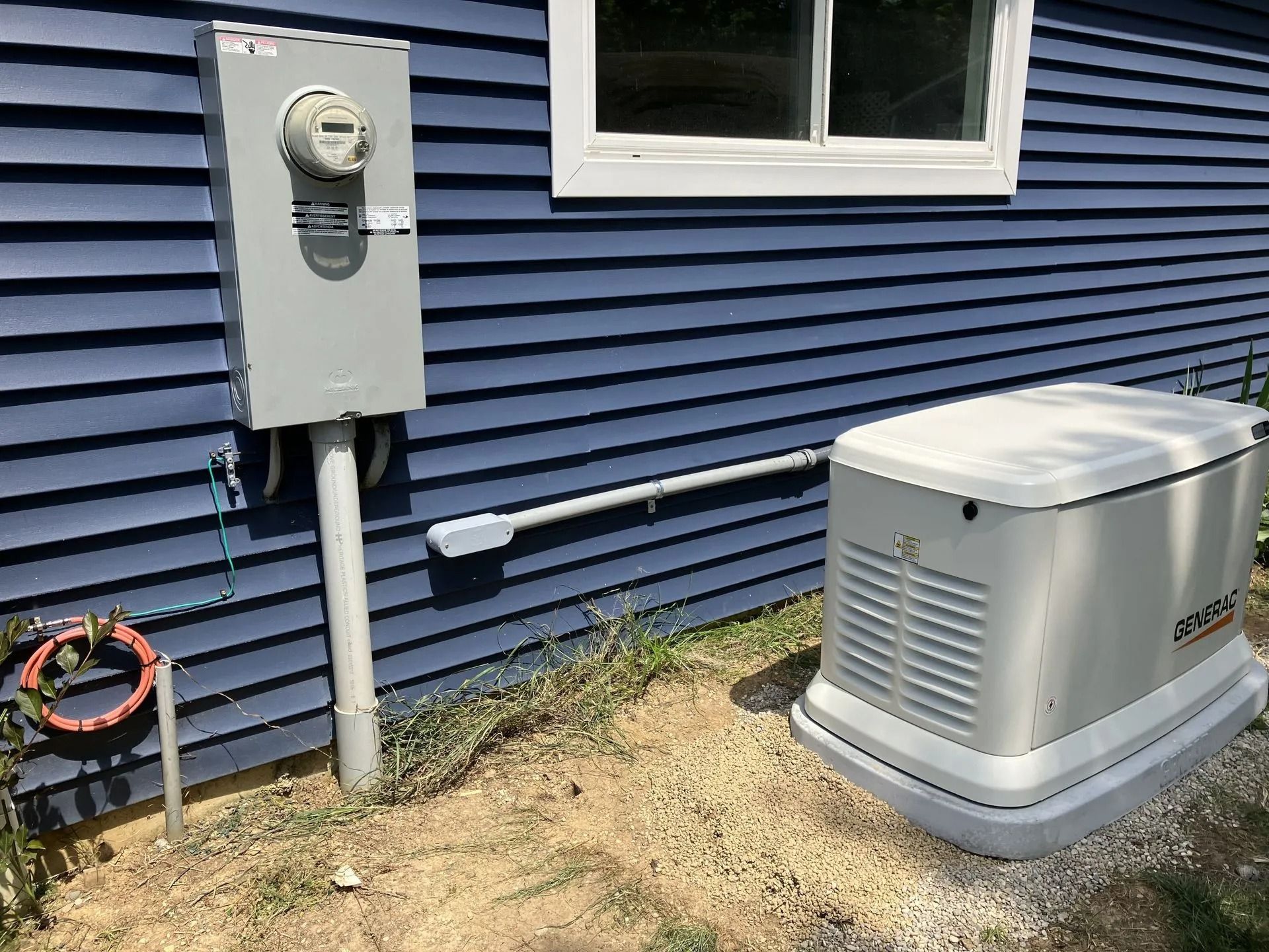 Blue house siding with electric meter, utility box, and outdoor generator on the side yard