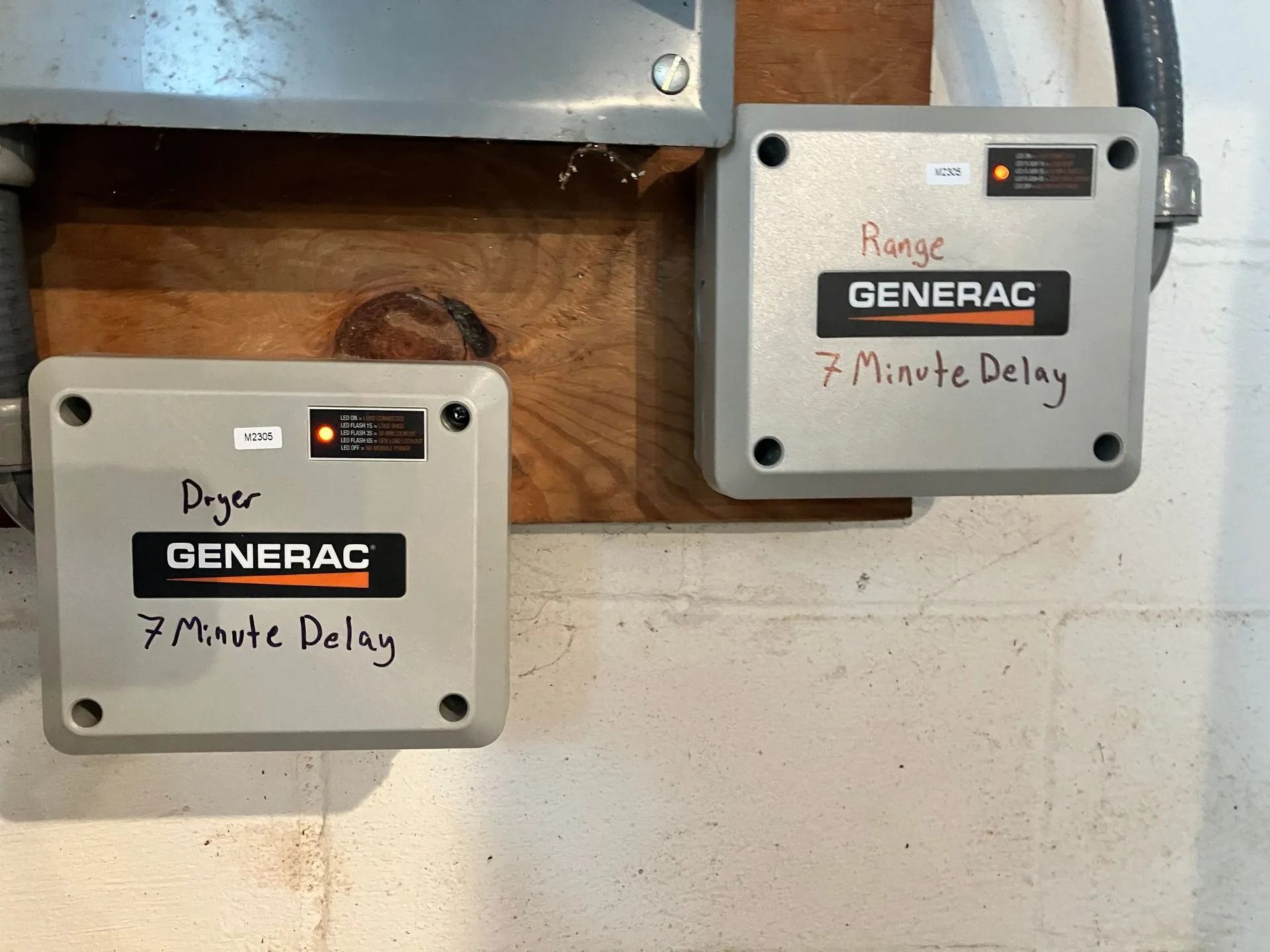 Two Generac 7-minute delay control boxes mounted on a wooden wall.