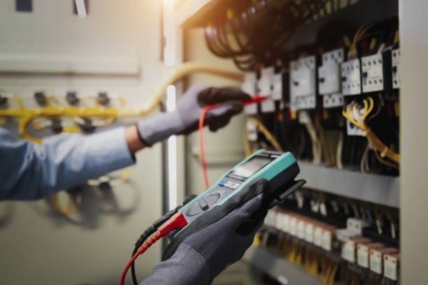 Technician testing electrical panel wiring with a multimeter in a utility room