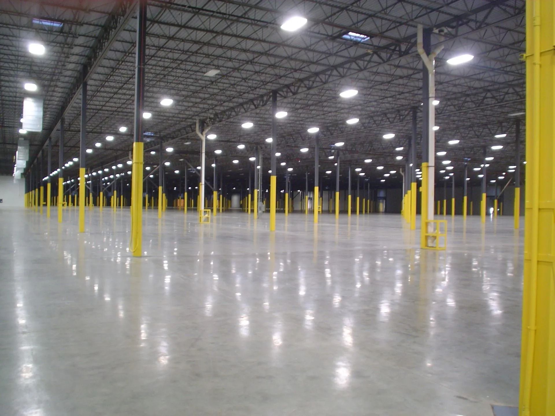 Empty warehouse interior with rows of yellow support columns and bright overhead lights