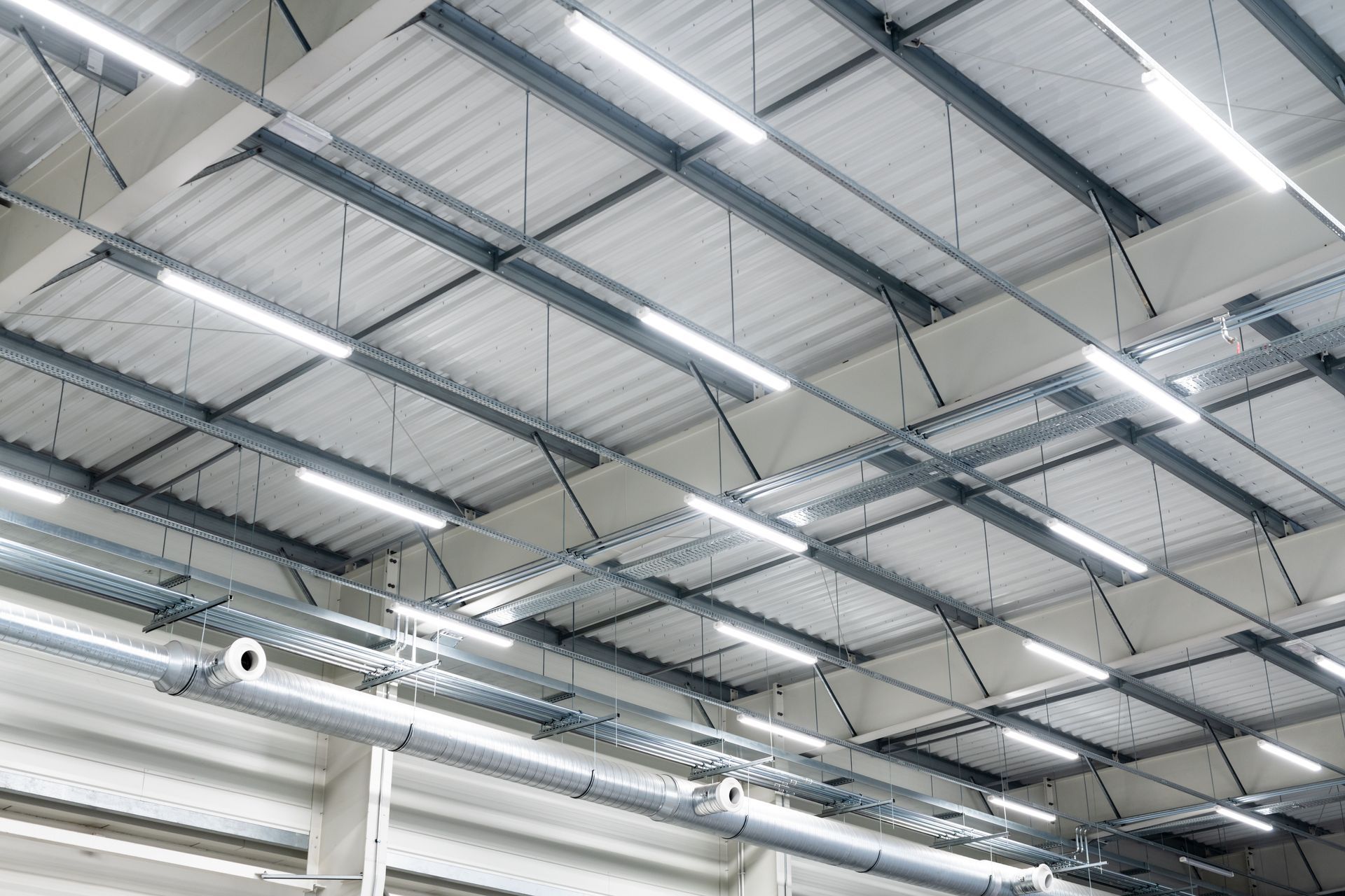 Interior of a warehouse with a high metal ceiling and rows of bright fluorescent lights