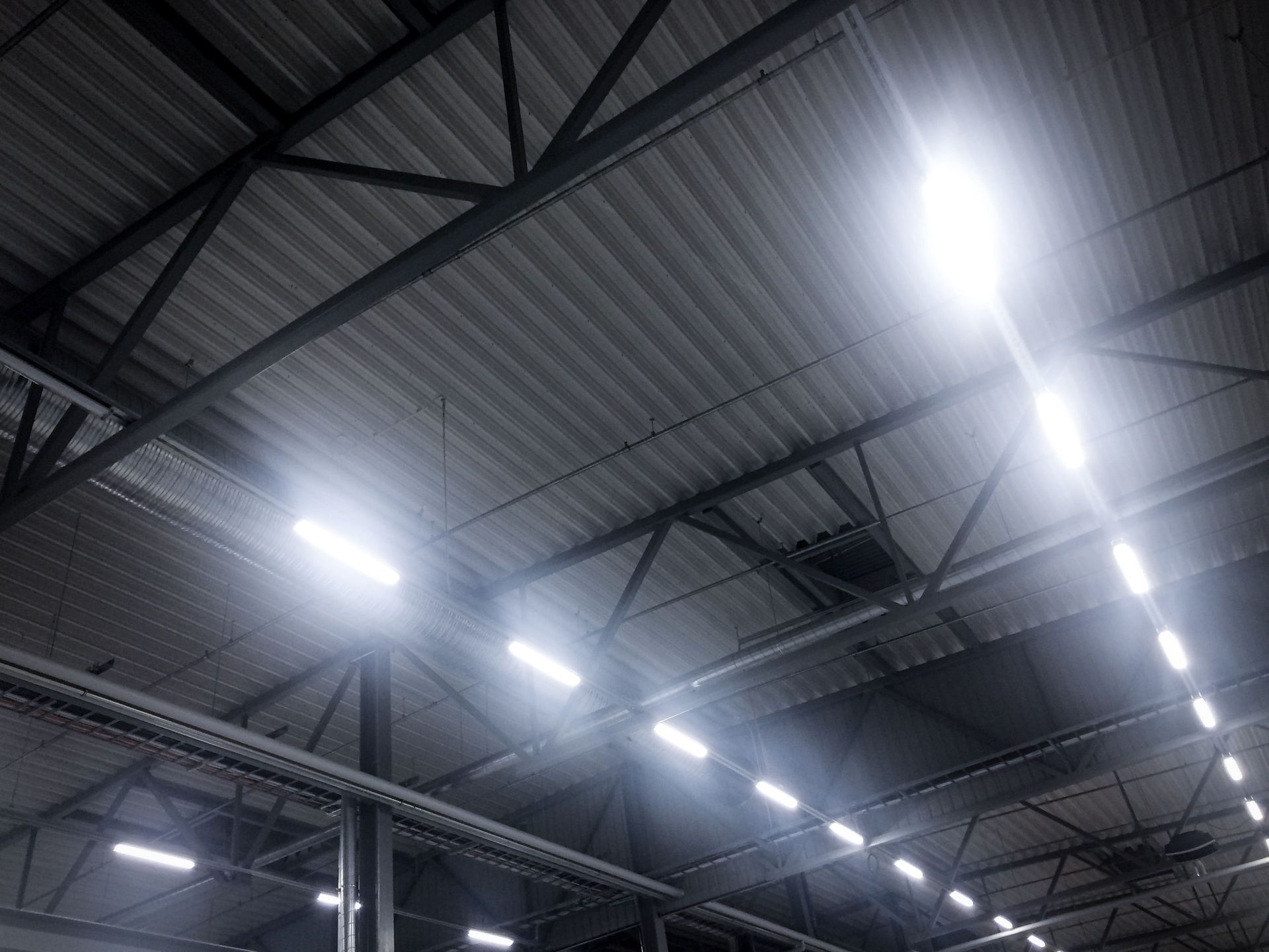 Industrial warehouse ceiling with metal beams and bright overhead lights