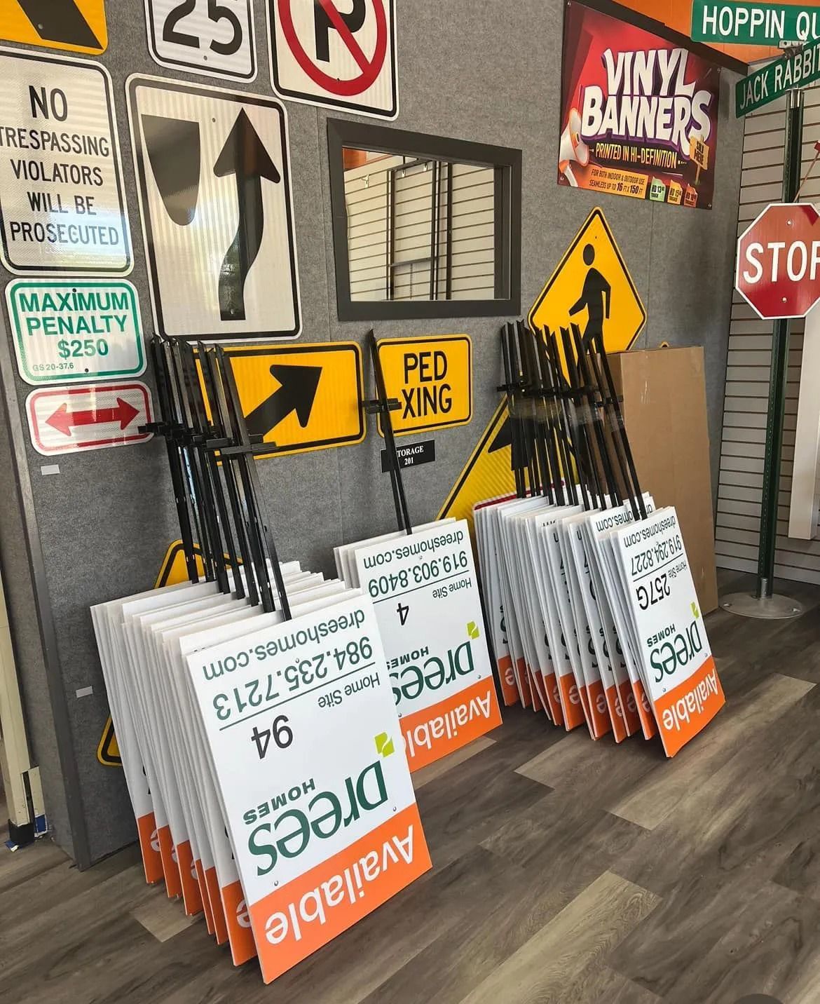 Store display with stacked reflective road signs and traffic-themed signs against a wall
