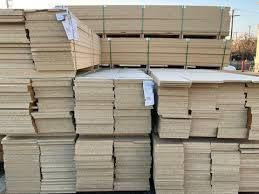 Stacks of lumber, bundled and ready for transport, outside on a bright day.