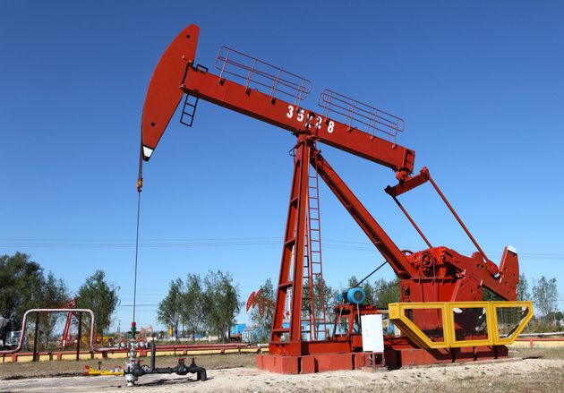 Red oil pumpjack in a field under a clear blue sky