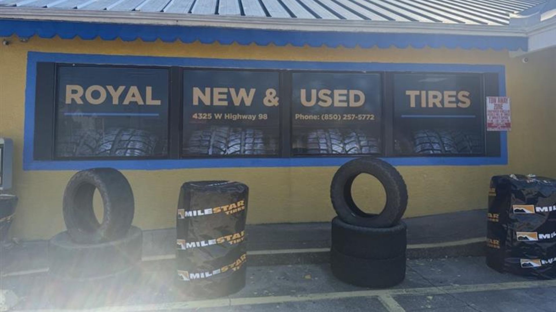 Royal New & Used Tires storefront with tires displayed outside. Yellow building with sign.