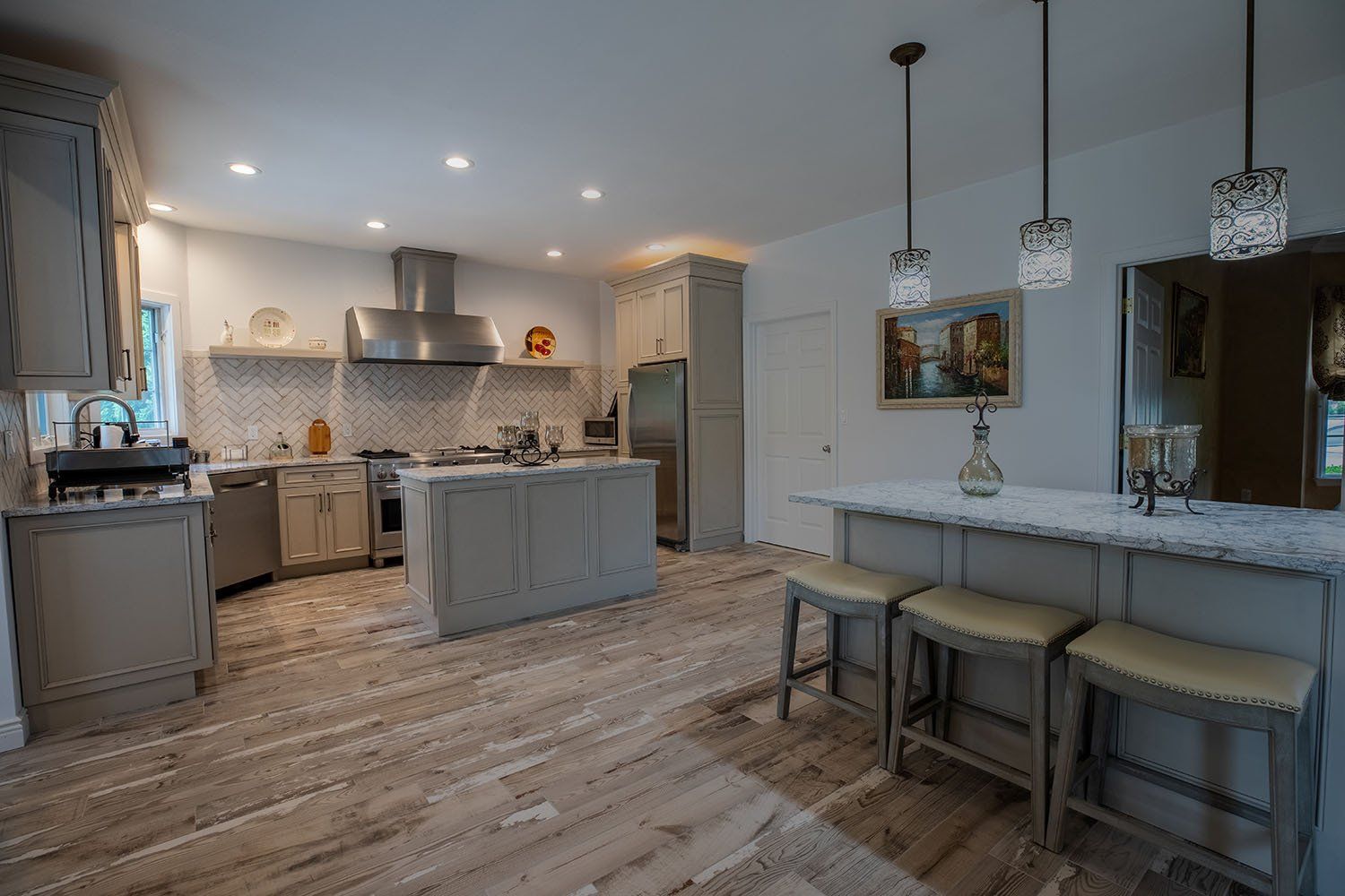 A kitchen with stools and a large island in the middle of the room.