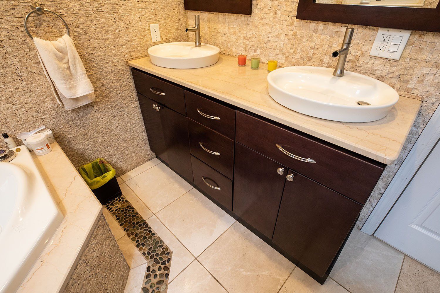 A bathroom with two sinks and a trash can