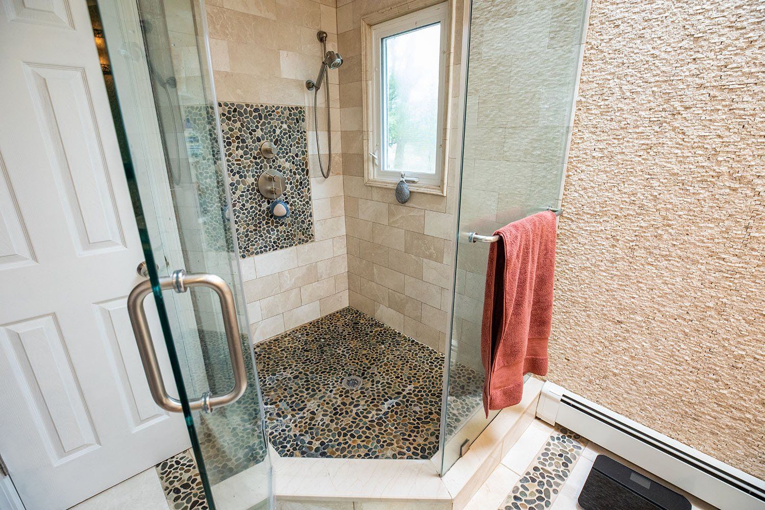 A bathroom with a walk in shower and a window.